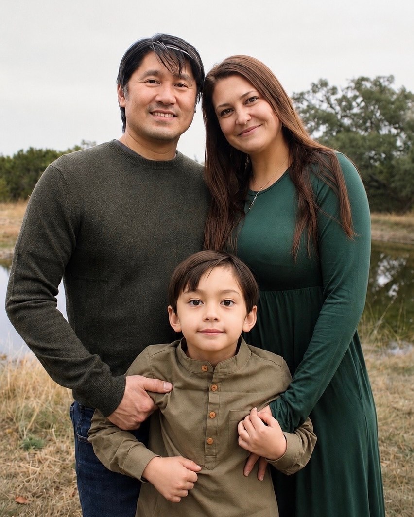 Sarah with her husband and son outdoors by a pond
